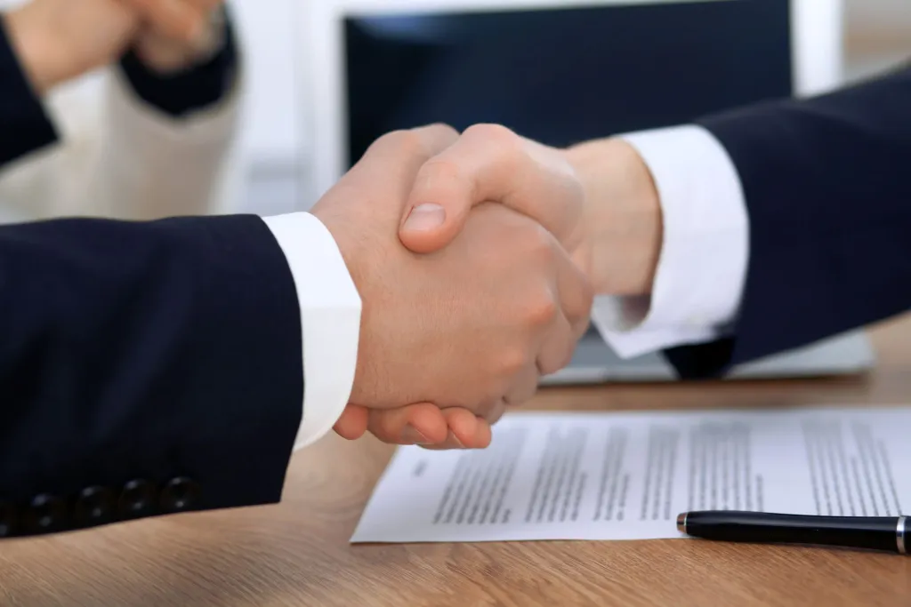 Two business professionals shaking hands to signify partnership or agreement.
